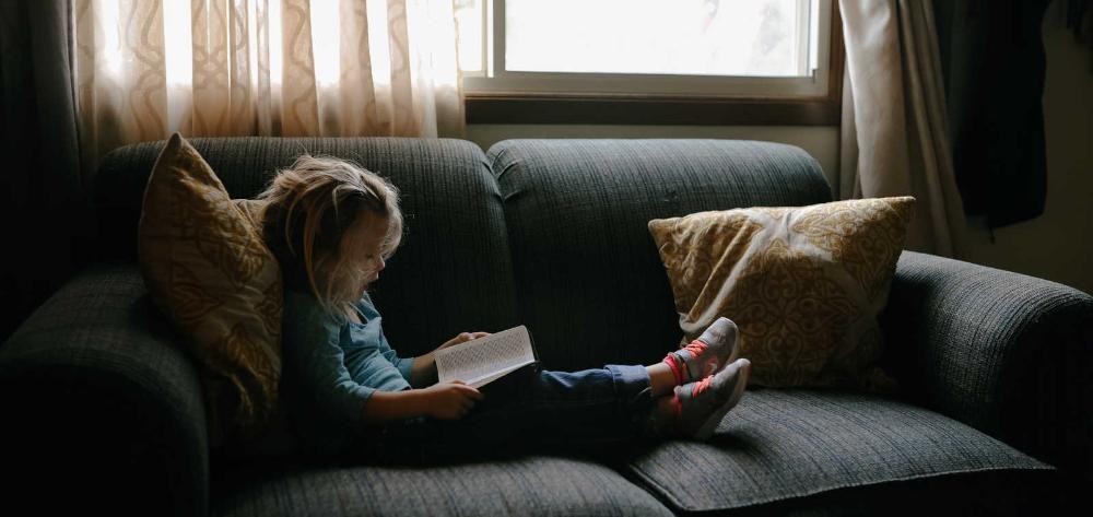 Nena llegint al sofà
