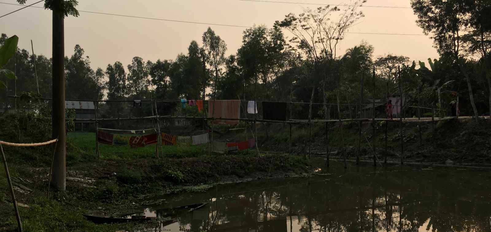 Roba estesa sobre una bassa a Bangladesh al capvespre.