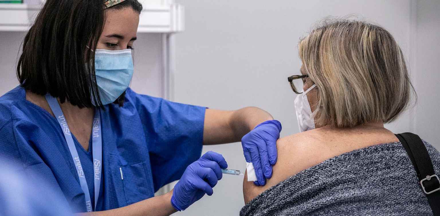 Nurse vaccinating a woman wearing a face mask against COVID-19.