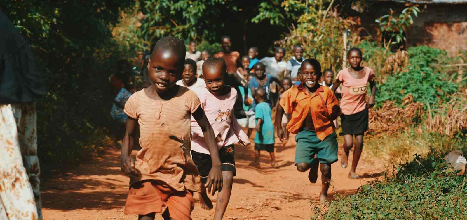 Smiling children running along a rural path in Sierra Leone.