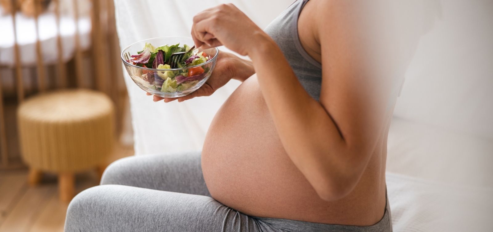 Pregnant woman sitting eating salad