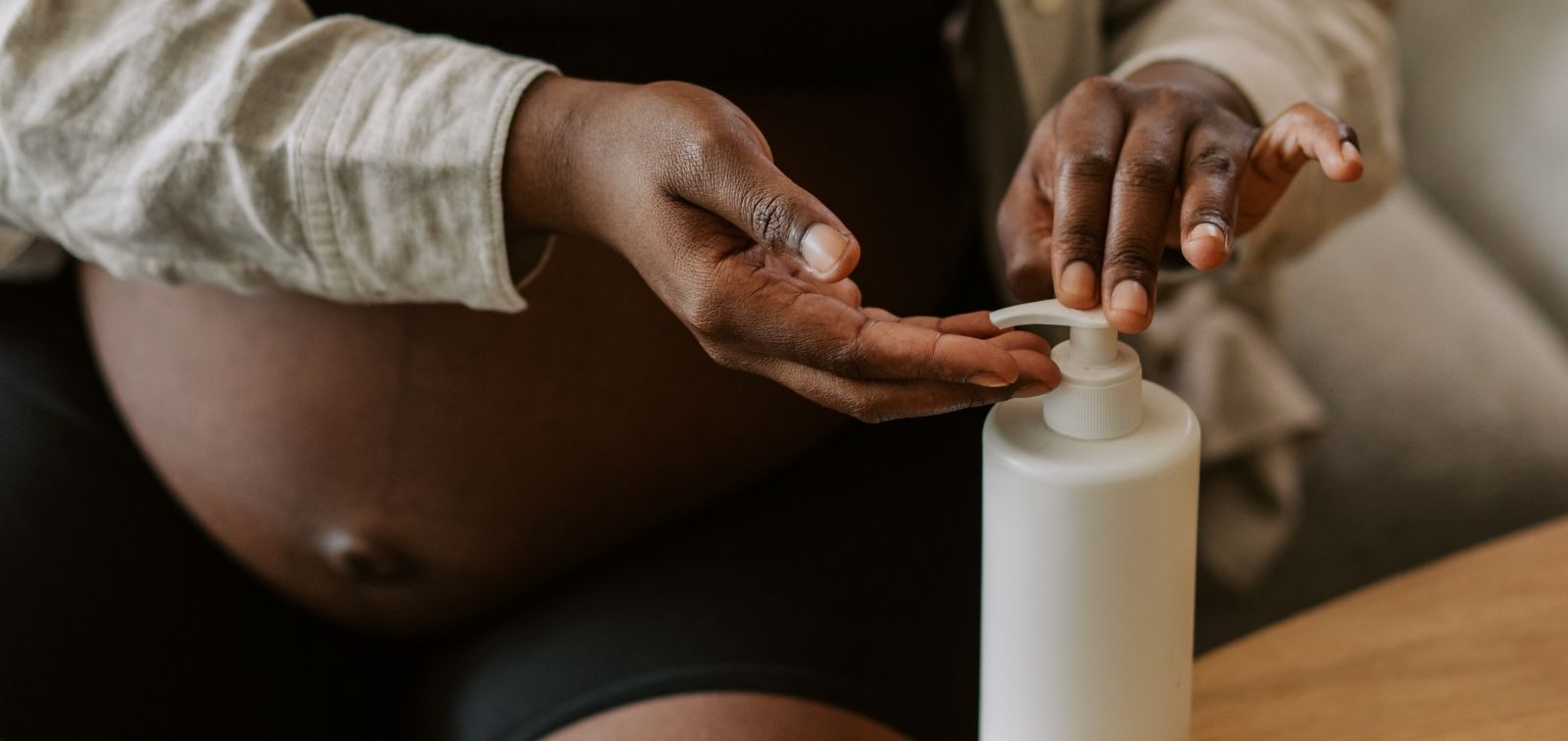 Mujer embarazada poniéndose crema en las manos