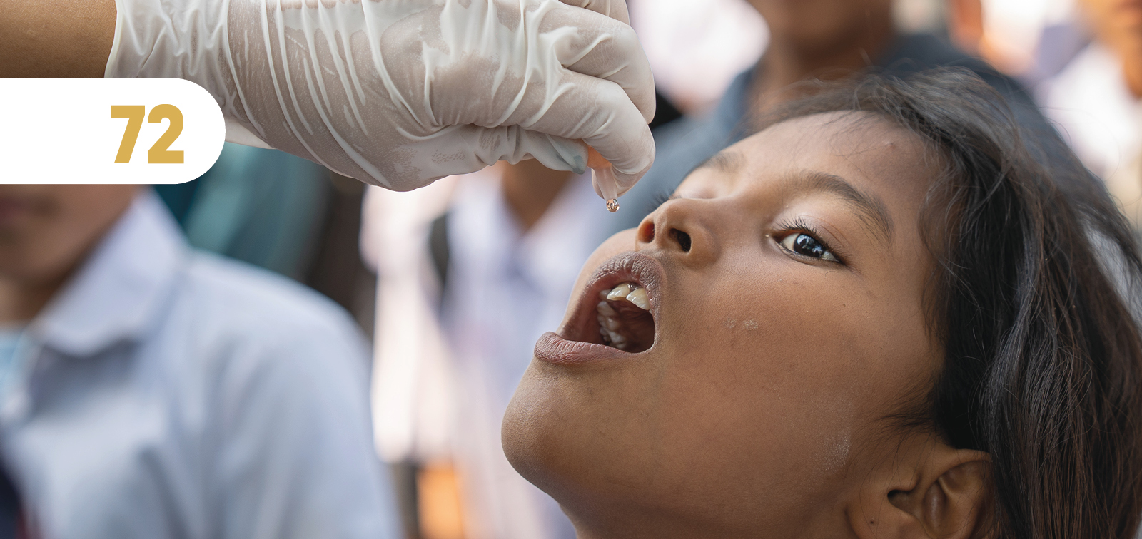 Una niña con la boca abierta recibe gotas de la vacuna de la polio administradas por un sanitario con guantes en Mae Sot, provincia de Tak (Tailandia).