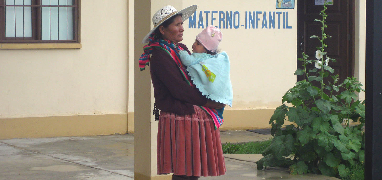 Mare amb el seu nadó en braços davant d'un centre de salut bolivià