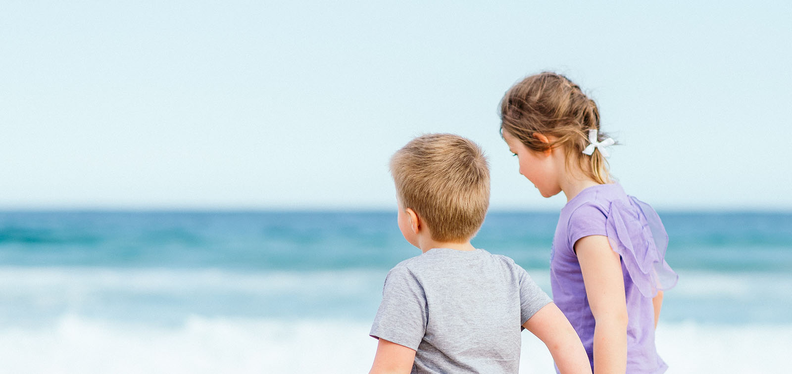 Un niño y una niña pasean en la playa
