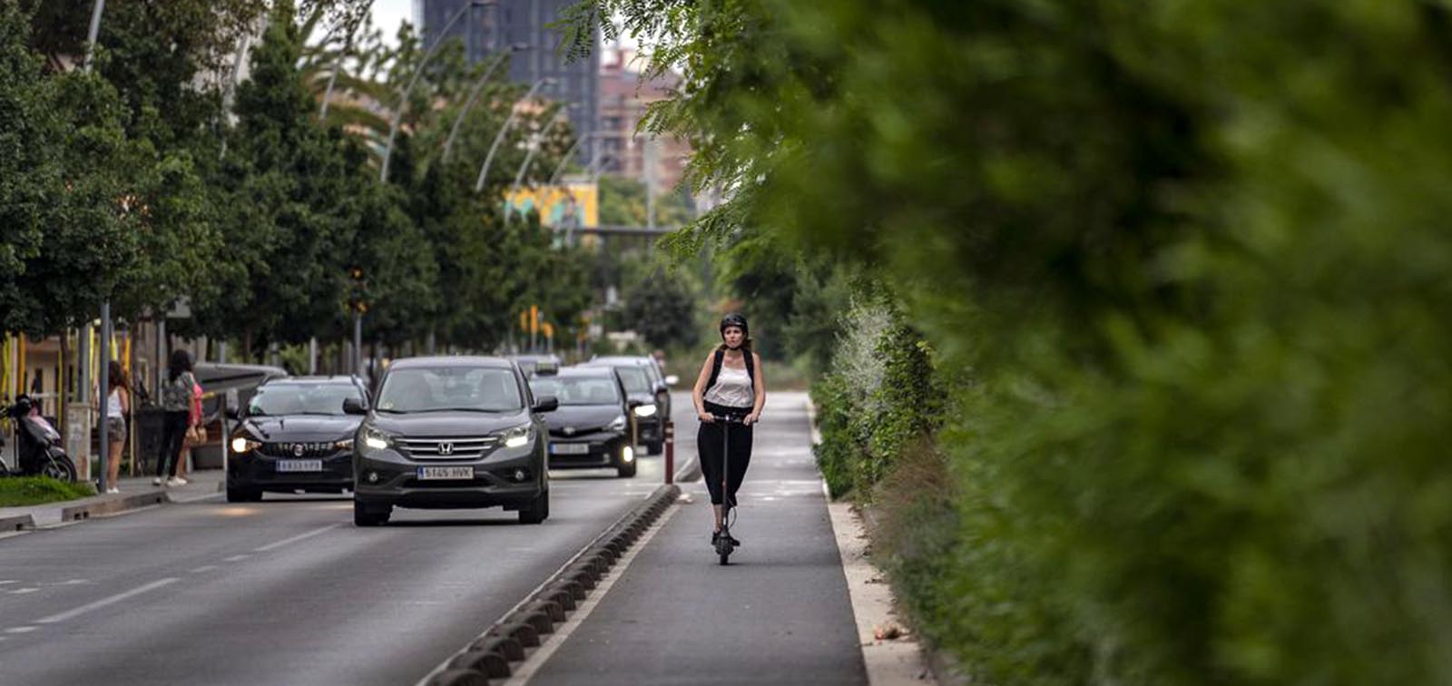 Tráfico en Barcelona y una chica en patinete por el carril bici