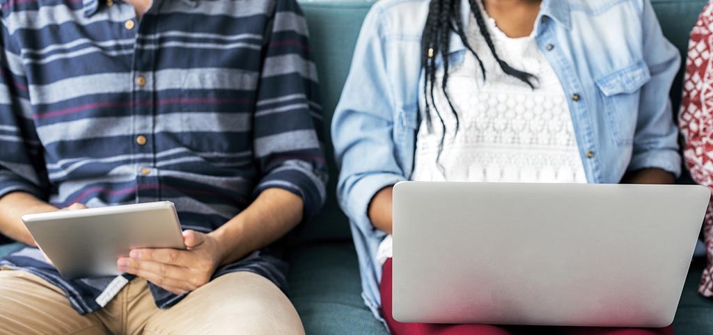 A boy and a girl that are using a laptop and a tablet