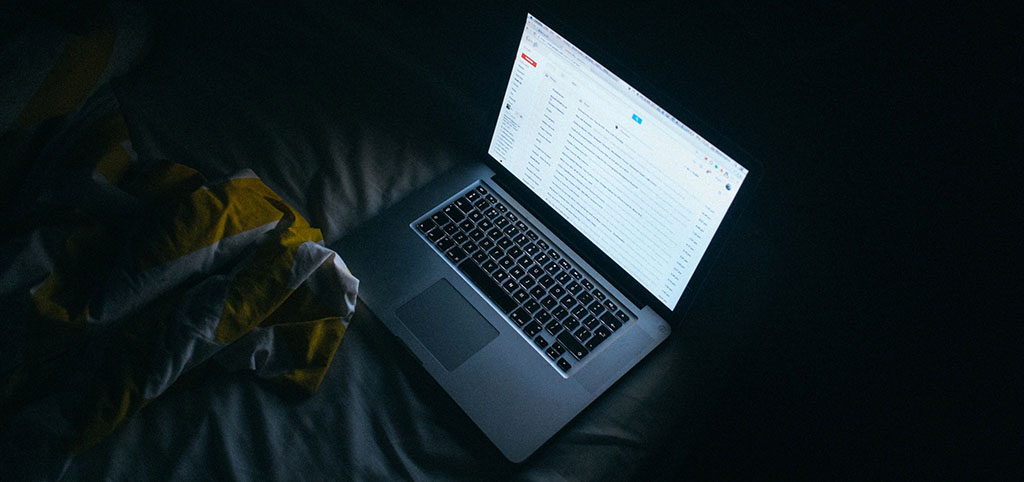 A laptop on a bed at night