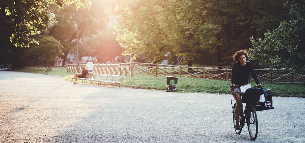 Una chica recorre en bicicleta el interior de un parque urbano