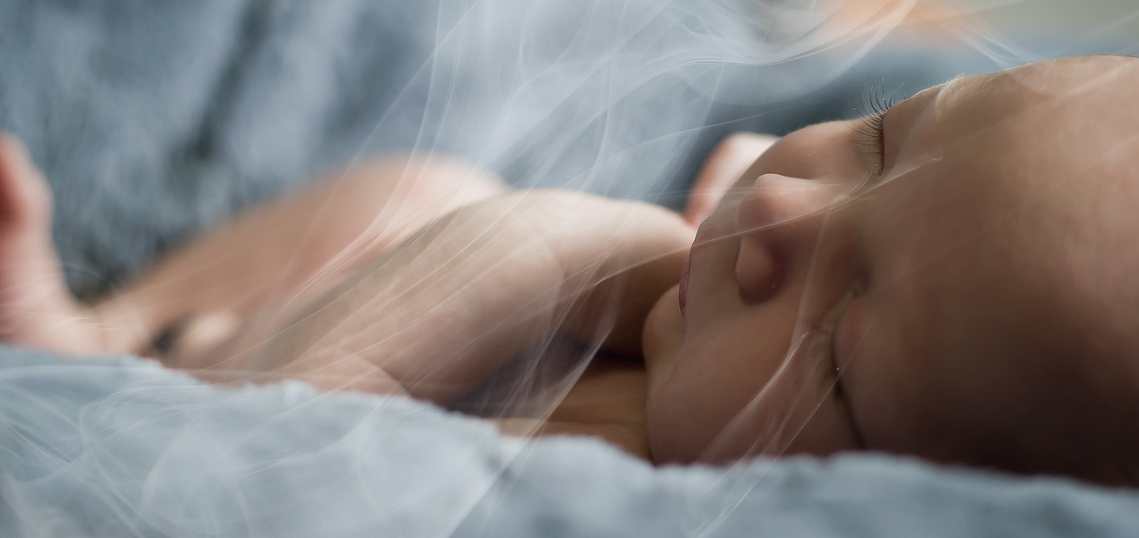 A newborn inhales tobacco smoke